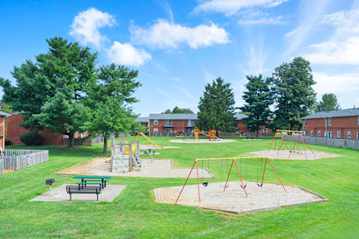 Apartment playground and picnic area at Mount Vernon, featuring play equipment, benches, and open space for outdoor activities.