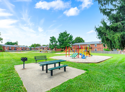 Apartment playground and picnic area at Mount Vernon, featuring play equipment, benches, and open space for outdoor activities.