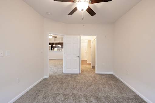 A room with a ceiling fan and carpeted floor.