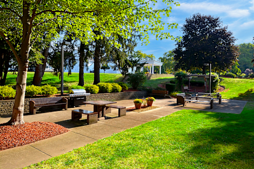BBQ and picnic area featuring benches, a grill, and trees at Kentwood Square Apartments.