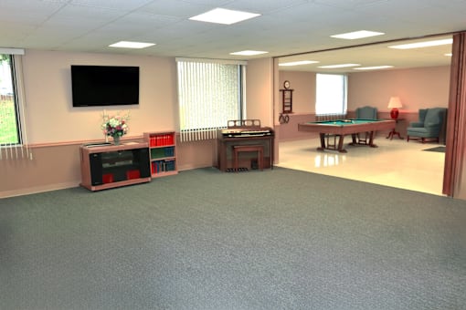 Entertainment area with a pool table, a television, and a small piano at Kentwood Square Apartments.