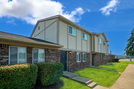 Exterior view of a building at Colonial Village Apartments, showcasing well-maintained landscaping and a classic design.