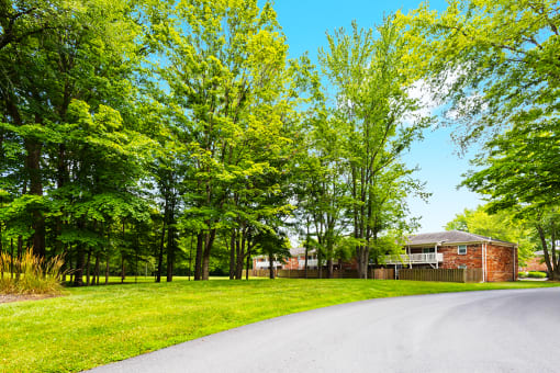 Exterior view of Hampton Court Apartments, surrounded by landscaped greenery and a tree-lined street.