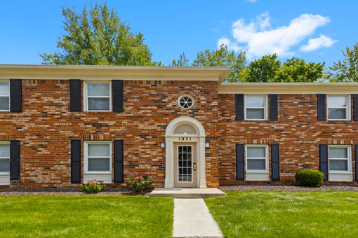 Exterior view of Hampton Court Apartments, showcasing the building's architecture with windows and well-maintained landscaping.
