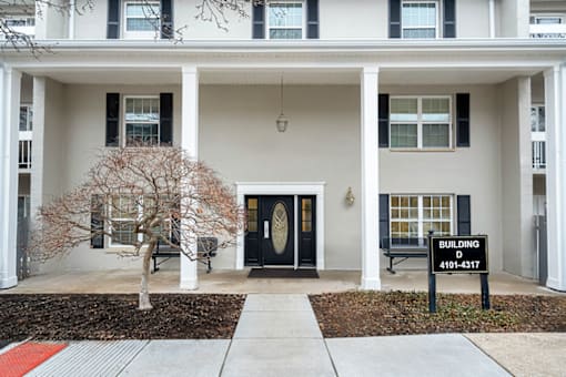 A white building with a black door and a sign that says "Building D" on it.