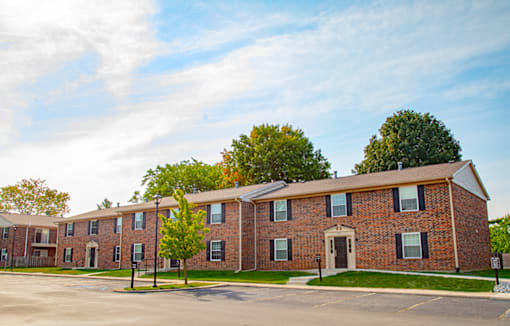 Exterior view of a building with a parking lot in front at Carriage House Apartments in Kendallville.