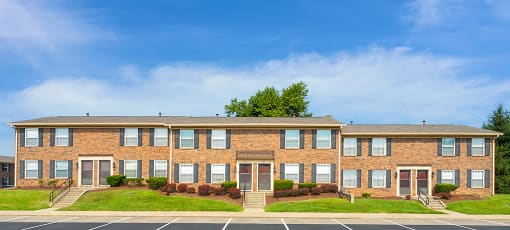 Exterior view of Carriage House Apartments in New Albany, showcasing the building's architecture and adjacent parking area for residents.