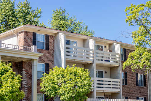 A multi-story apartment building with balconies and trees in front.