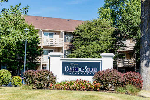A sign that says Cambridge Square Apartments in front of a building.