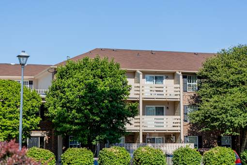 A large apartment building with a brown roof and a balcony on the second floor.