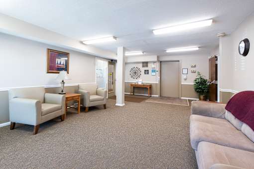 A living room with a grey carpet and white walls.