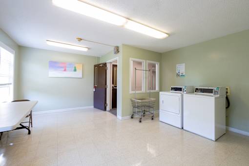 A room with a white table and a white refrigerator.