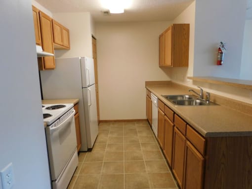 Kitchen with white appliances and wooden cabinets at Chapelgate Park Apartments