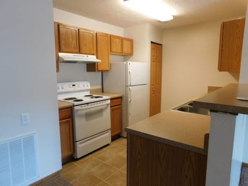 Kitchen with white appliances and wooden cabinets at Chapelgate Park Apartments