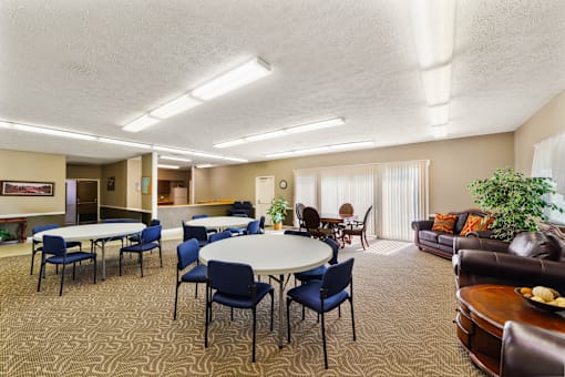 Clubhouse at Fairington Apartments in Anderson with tables and chairs and a couch.