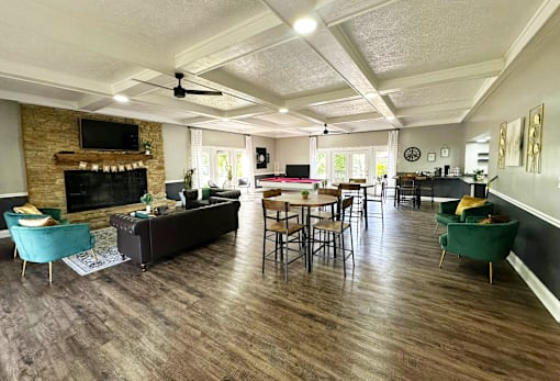 Interior of the clubhouse at Woodbridge Apartments in Bloomington, featuring a fireplace furniture, pool table, and seating areas.