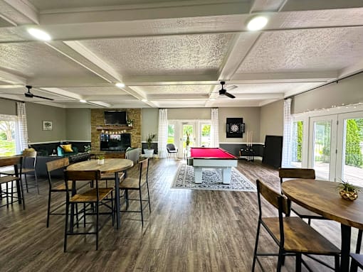 Interior of the clubhouse at Woodbridge Apartments in Bloomington, featuring furniture, pool table, and seating areas.