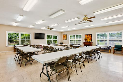 Community clubhouse at Blairwood Apartments in Louisville, featuring, a room with tables and chairs and a ceiling fan.