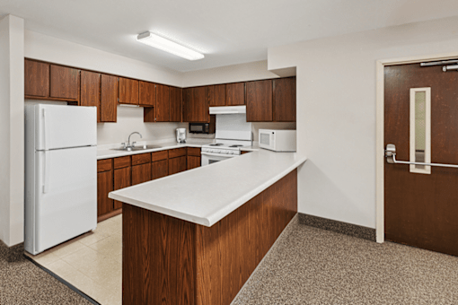 A kitchen with white appliances and brown cabinets.