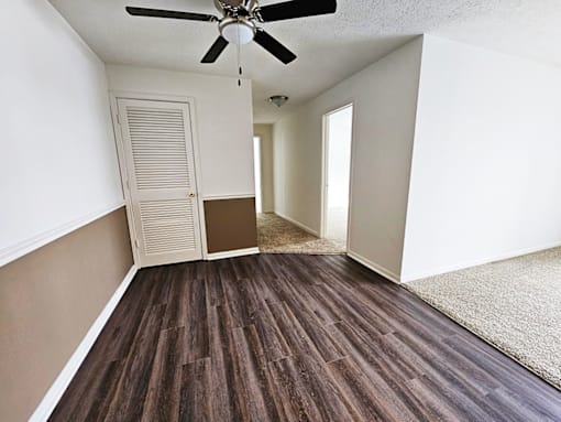 A room with a ceiling fan and wooden flooring.
