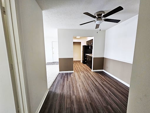 A room with a ceiling fan and wooden flooring.