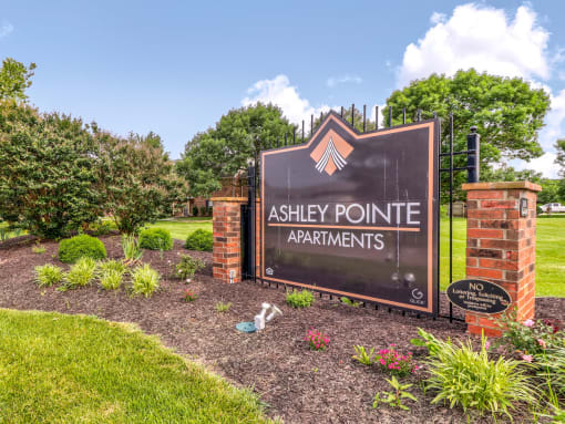 Community entrance at Ashley Pointe Apartments with brick sign and flower beds.