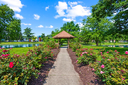 Gazebo surrounded by red flowers and a concrete walkway at Fairington Apartments in Clarksville, Indiana.