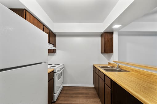 Kitchen in a 1-bed, 1-bath apartment at Carriage House Glendale, featuring a stove, a wooden countertop, refrigerator, and sink in a functional layout.