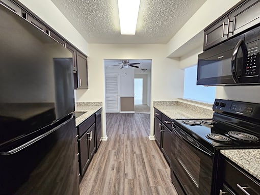 A kitchen with black appliances and wood floors.