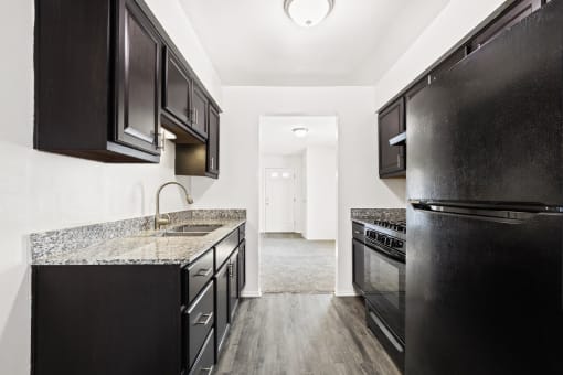 Kitchen in a two-bedroom, one-bath Windsor Park apartment, featuring black appliances, granite countertops, and cabinetry.