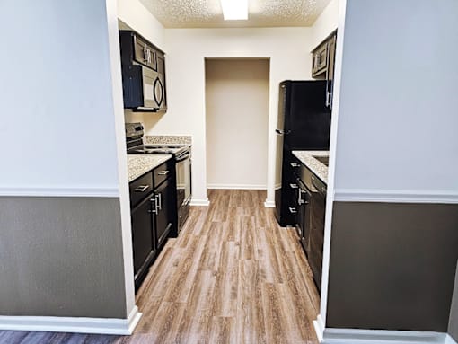 A kitchen with black appliances and wood flooring.