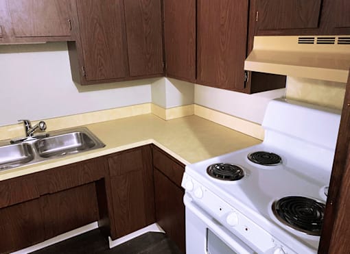 Kitchen with a stove, sink and  wooden cabinets at Marshall House Apartments.