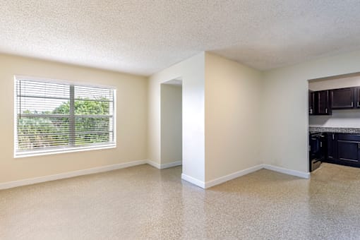 Living room in a 2-bed, 1-bath apartment at Cambridge Square Apartments in Lauderdale Lakes, featuring a spacious layout and natural light from large windows.