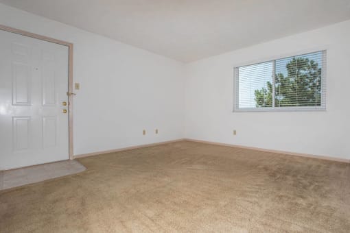 Carpeted living room with a window in a 2 bedroom apartment at King's Landing Apartments.