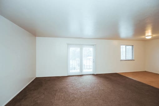Spacious living room in Henderson Court Apartments with carpeted floors and balcony access.