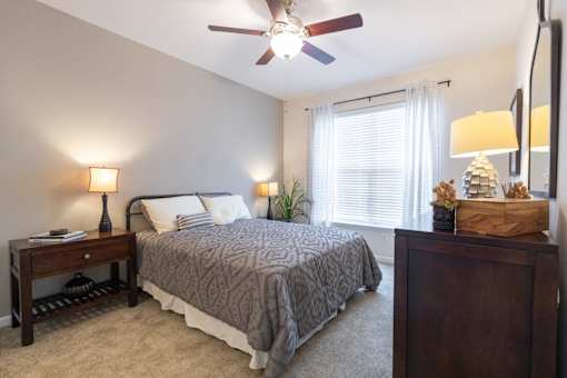 A bedroom with a bed, nightstand, and a ceiling fan.
