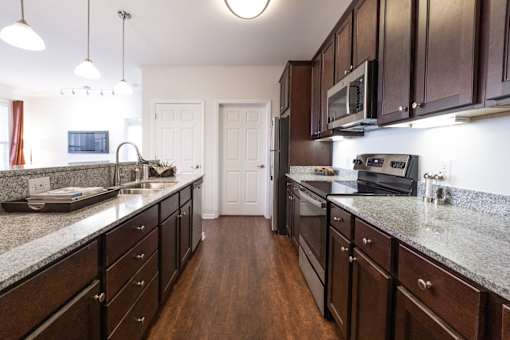 A kitchen with dark wood cabinets and granite countertops.