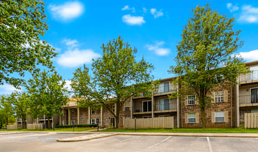 Apartment complex with a parking lot in front.
