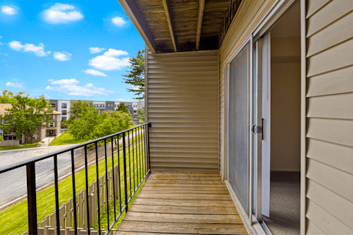A balcony with a black railing and a view of a street and buildings.