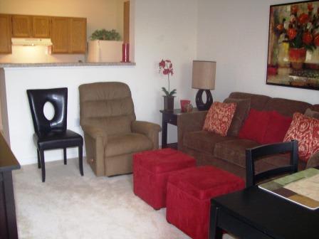 A living room with a brown couch, a chair, and a table with a lamp.