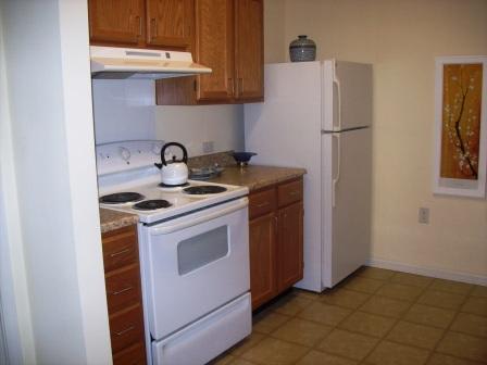A small kitchen with a white stove and refrigerator.