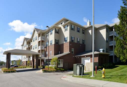 A large apartment complex with a parking lot in front.