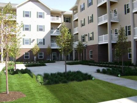 Apartment complex with green lawns and trees.