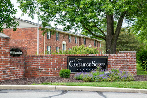A brick wall with a sign that says Cambridge Square Apartments.