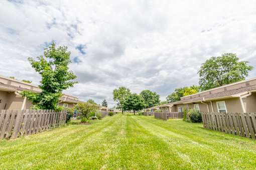 A grassy pathway leads through a residential area with houses on either side.