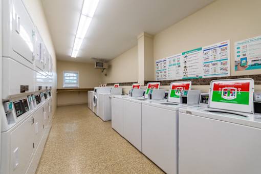 A laundromat with washers and dryers lined up and instructions on the wall.
