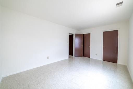 Three brown doors in a white room.