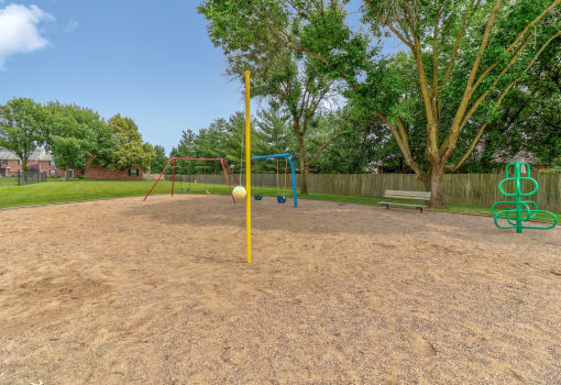 Playground at Ashley Pointe Apartments with swing sets, tetherball and climbing equipment