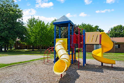 A playground with a yellow slide and a blue and yellow tower.