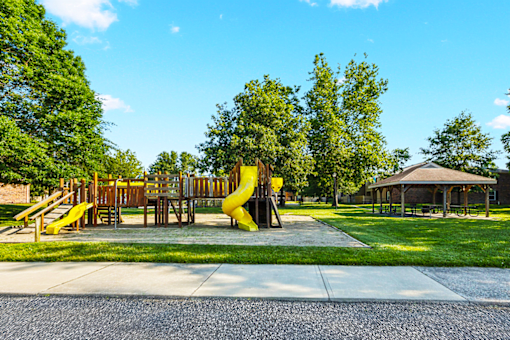 Playground and picnic area at Jamestown Apartments in Seymour, Indiana, featuring benches, tables, and play structures.